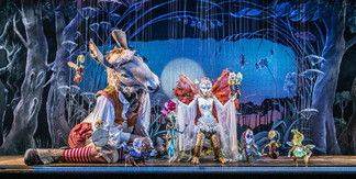Fantasievolle Bühneninszenierung mit Figuren und Masken in märchenhaftem Bühnenbild