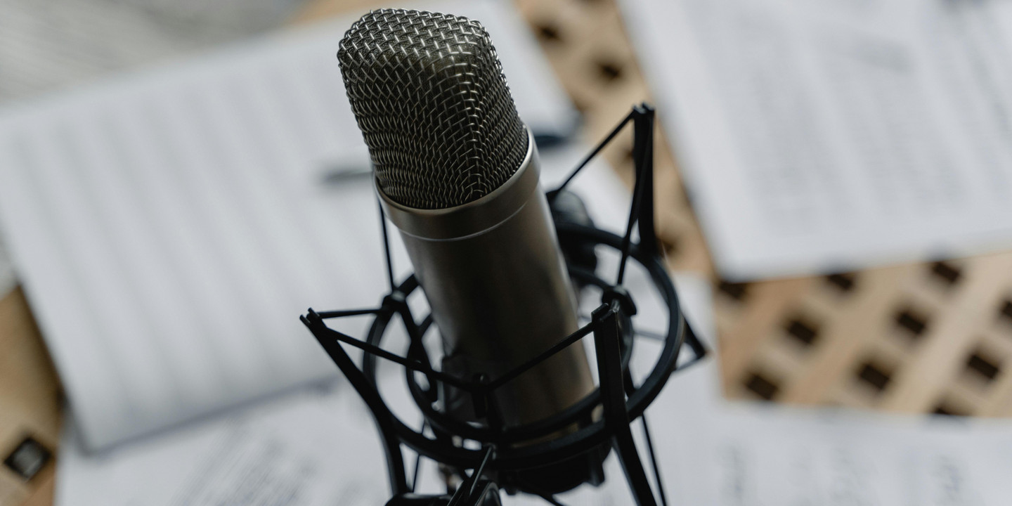 Studiomikrofon in Nahaufnahme, umgeben von unscharfen Notenblättern.