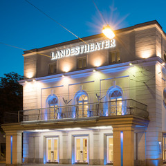 Abendlich beleuchtetes Salzburger Landestheater mit klassischer Fassade