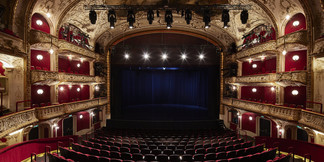 Blick auf beleuchtete Theaterbühne und goldverzierten Zuschauerraum