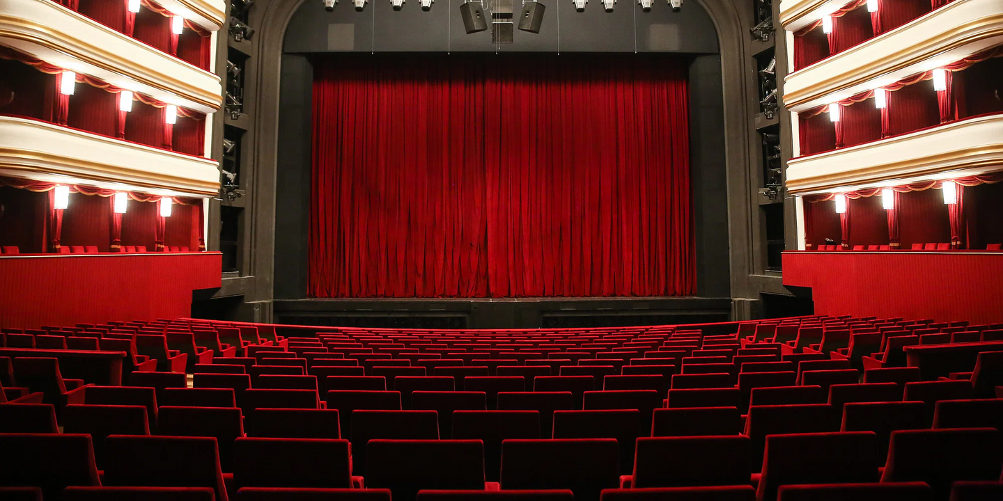 Leerer Theatersaal mit rotem Vorhang und modernen Sitzreihen