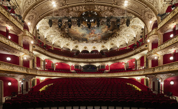 Prunkvoller Theatersaal des Volkstheaters Wien mit rotem Samt, goldenen Verzierungen und bemalter Decke.