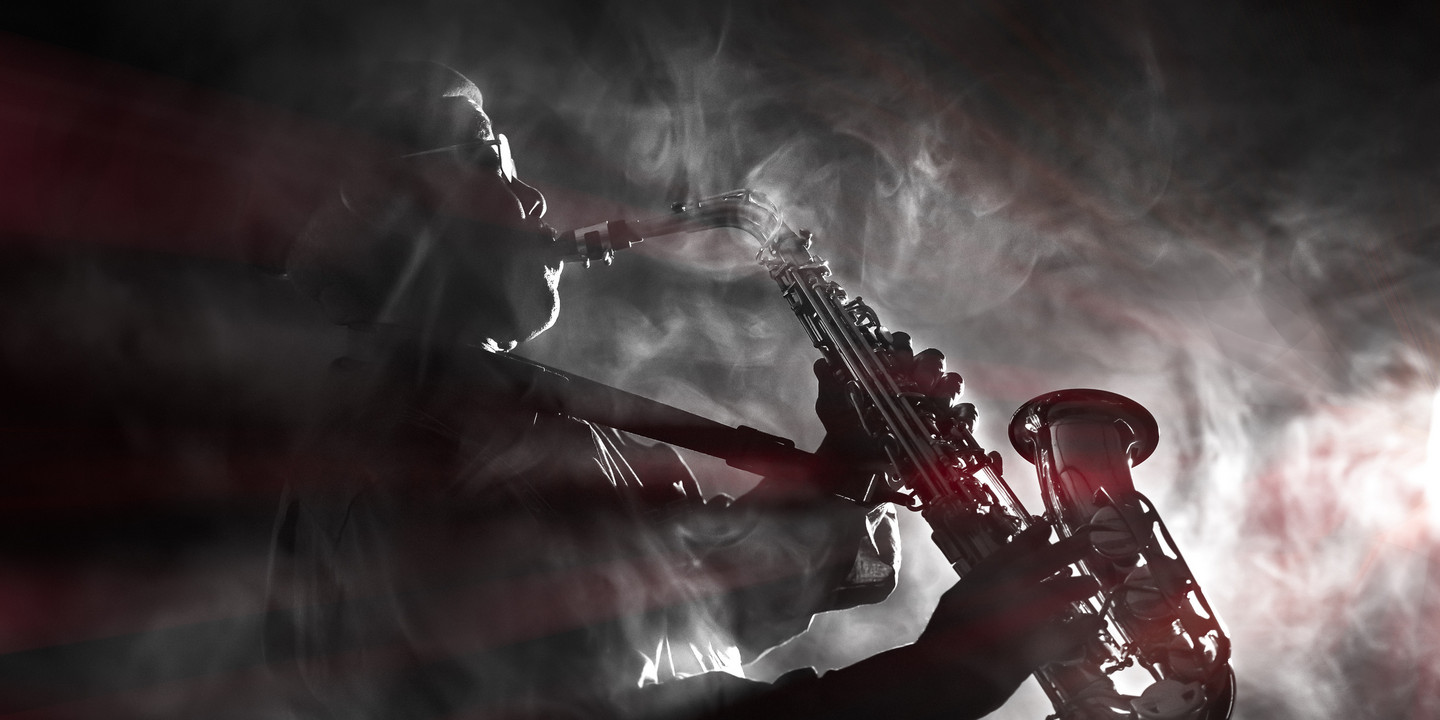 Jazzsaxophonist im Gegenlicht mit Nebel und dramatischer Lichtstimmung