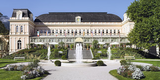 Historisches Kurhaus mit Springbrunnen und Gartenanlage in Bad Ischl bei Sonnenschein.