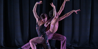  Zeitgenössisches Tanzduo in expressiver Pose vor schwarzem Bühnenvorhang