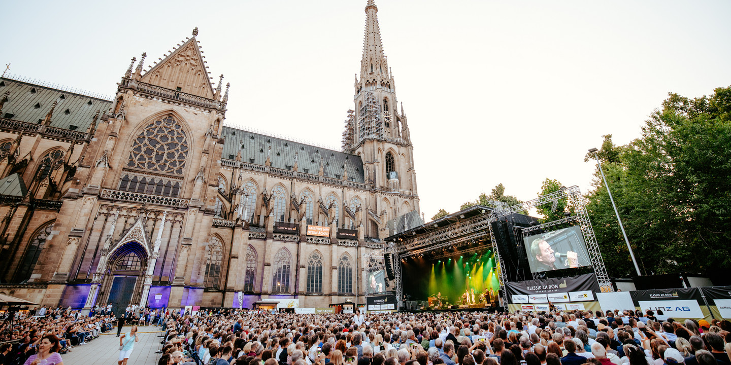 Großes Open-Air-Konzert vor dem Mariendom in Linz mit Bühne, Publikum und Abendstimmung.